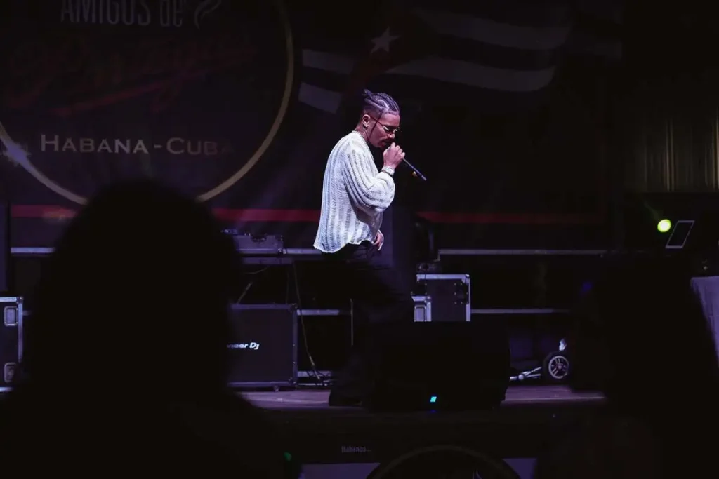 Haned Mota si esibisce sul palco principale del XX Encuentro Amigos de Partagás a Matelica, davanti al logo dell'evento e alla bandiera cubana stilizzata.