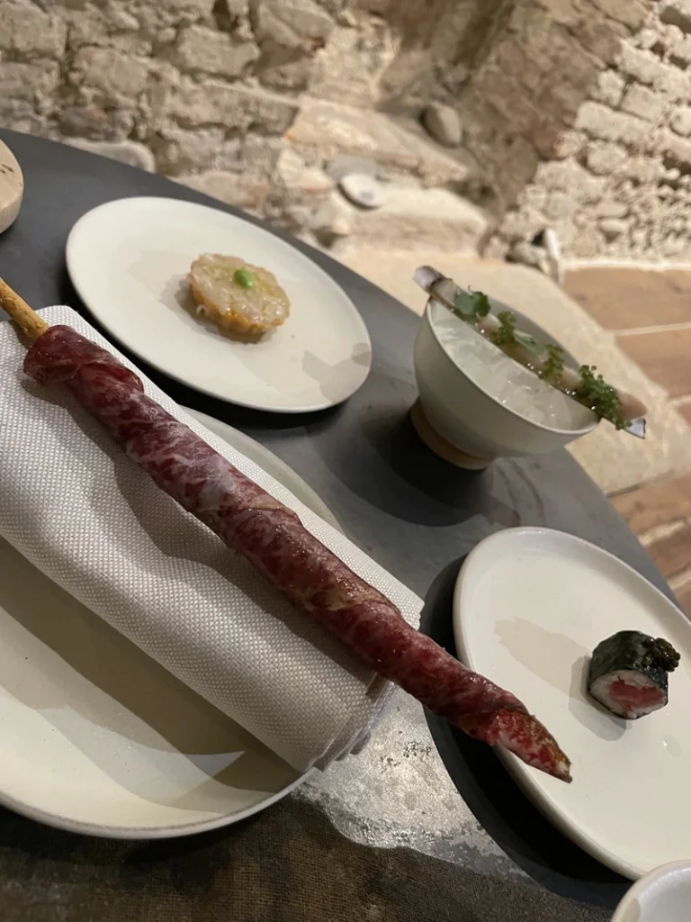 Selezione di antipasti della formula omakase da Akoya a Torino, tra cui un grissino avvolto in Wagyu, nigiri con caviale e assaggi di pesce crudo.