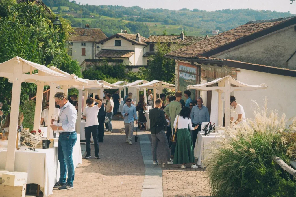 Persone e operatori di settore durante una degustazione ai banchi d'assaggio all'aperto di vini dell'Oltrepò Pavese.