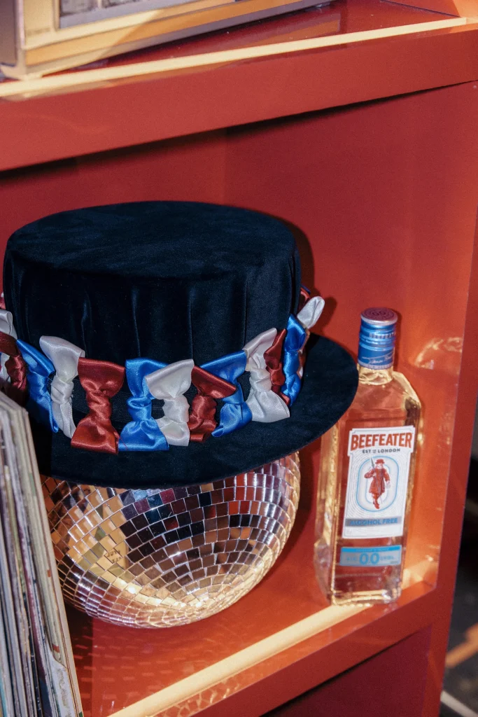 Bottiglia di Beefeater 0.0% analcolico posizionata accanto a una strobosfera e un cappello di Jay Kay da collezione.