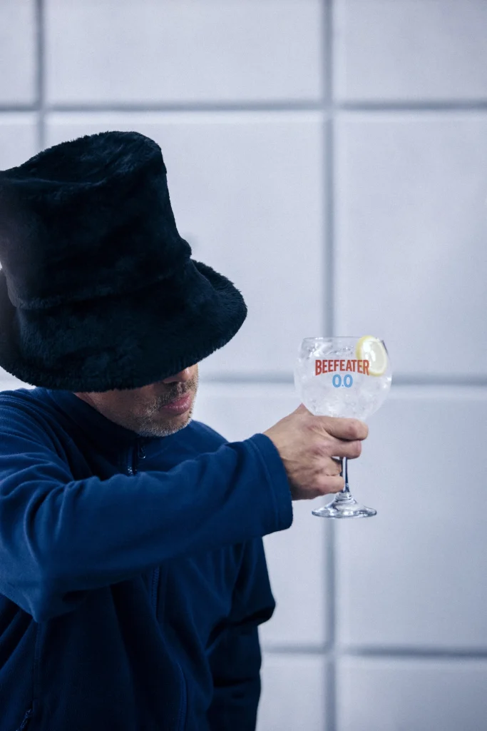 Jay Kay dei Jamiroquai con cappello nero che tiene in mano un cocktail Beefeater 0.0% and Tonic con limone.