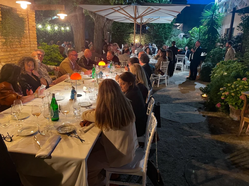 Lunga tavolata all'aperto di sera durante la cena posizionata nel giardino per il quinto anniversario dell'Habanos Terrace.