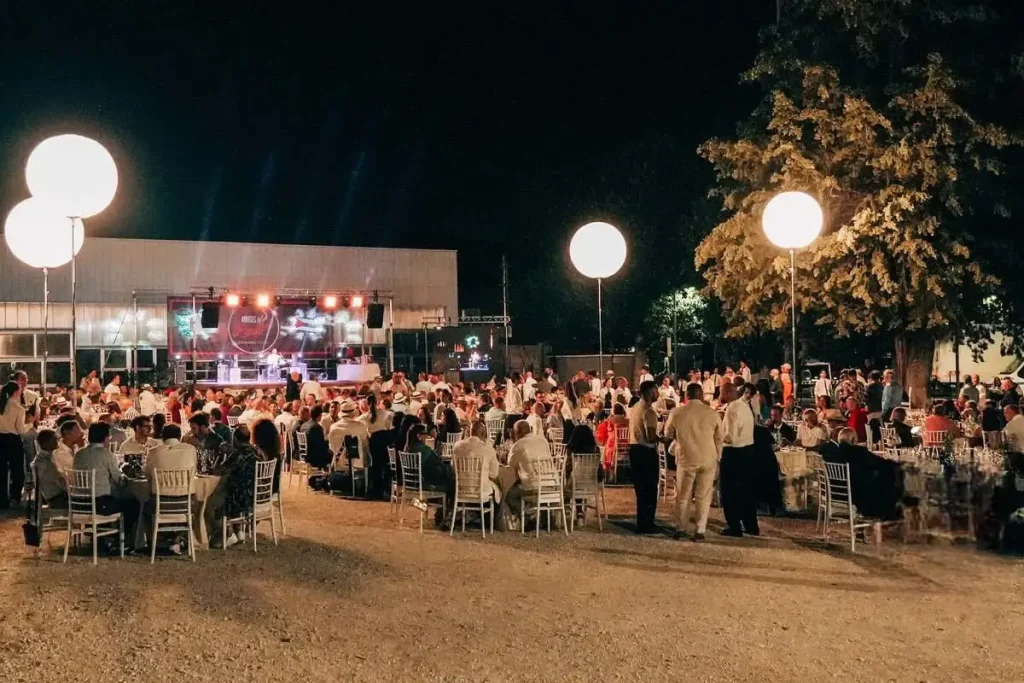 Panoramica all'aperto della cena di gala del XX Encuentro Amigos de Partagás con tavoli rotondi, ospiti elegantemente vestiti e grandi palloni luminosi a illuminare la serata.