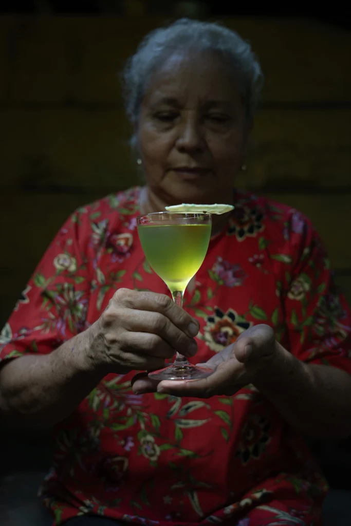 Una donna della comunità locale di Cartagena tiene in mano un calice con il cocktail Santa Maria di Alquímico.