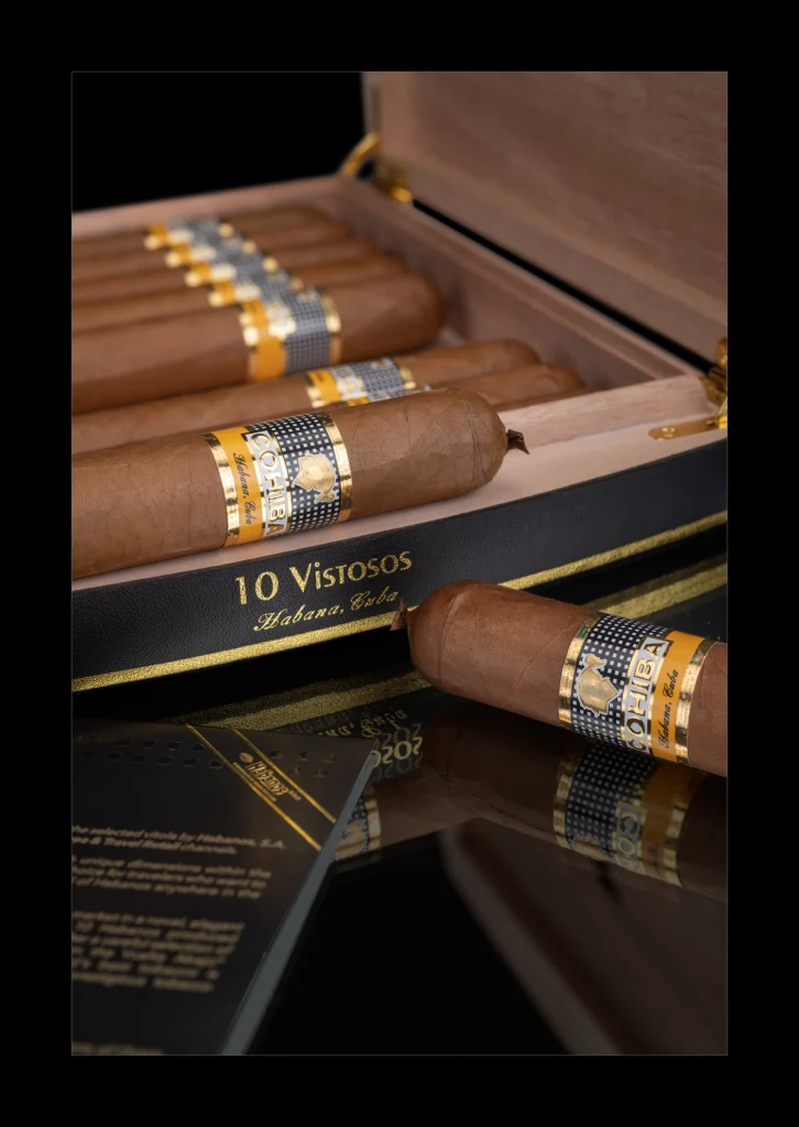 Dettaglio della testa con pigtail e dell'anilla del sigaro Cohiba Vistosos adagiato davanti all'humidor da viaggio.