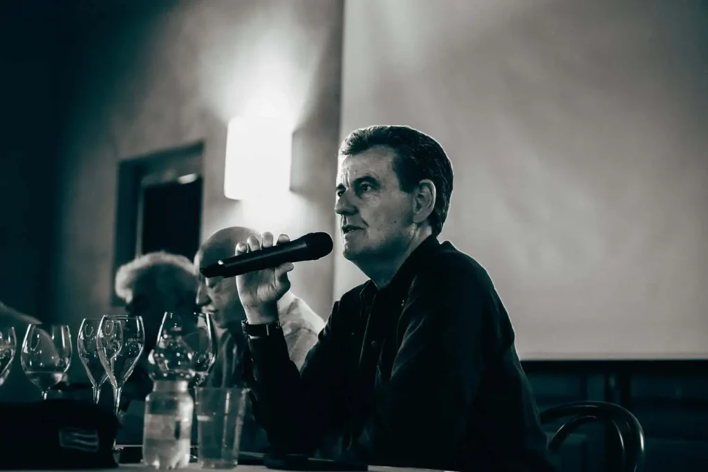 Marcello Lunelli al microfono mentre effettua l'analisi sensoriale in abbinamento ai calici di vino.