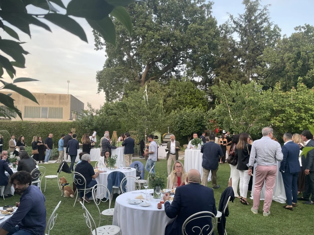 Ospiti e appassionati di fumo lento riuniti nei tavoli all'aperto nel giardino del Ristorante Andreina a Loreto.