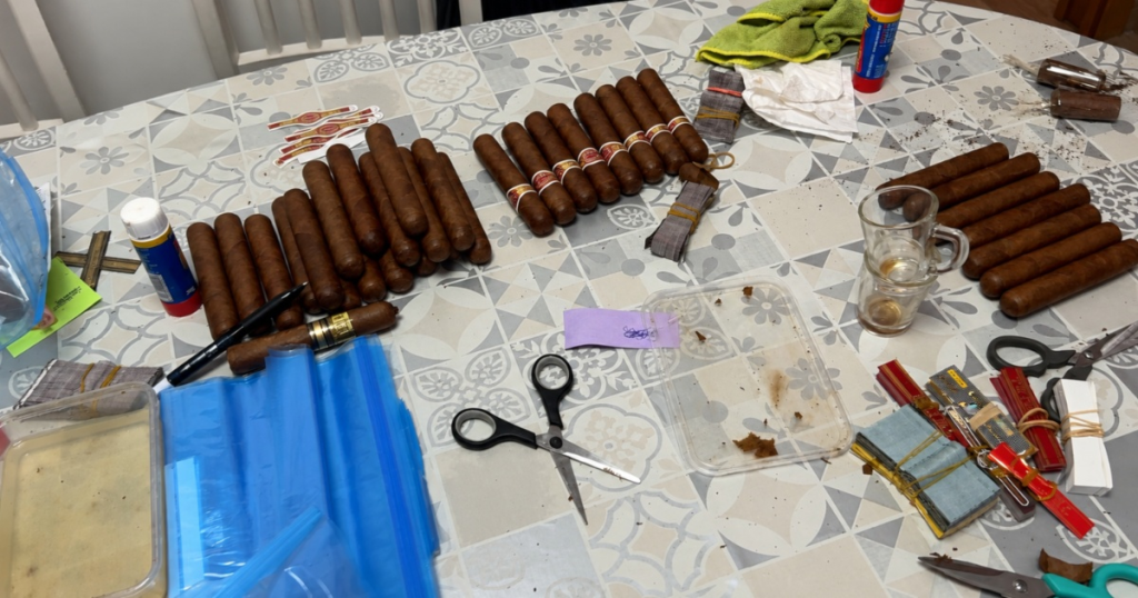 Il tavolo da lavoro utilizzato dai falsificatori con decine di sigari spogli, colla, forbici e le anille contraffatte pronte per essere applicate per imitare i sigari Cohiba.