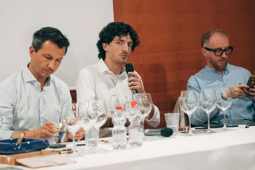 Un relatore interviene al microfono durante il seminario Alma Mia affiancato dagli esperti al tavolo della presidenza a Matelica.