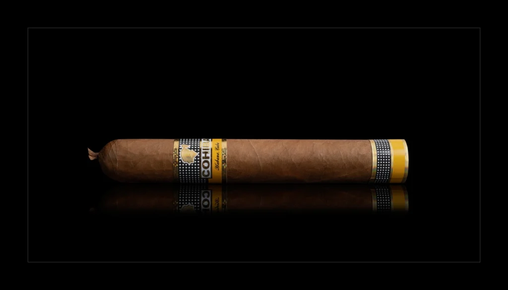 Sigaro cubano Cohiba Vistosos Vitola Dinoras con anilla classica e finitura a pigtail su sfondo nero.