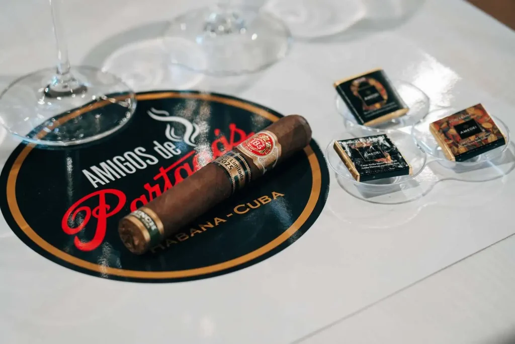 Il sigaro Punch Princesas Edición Limitada 2025 adagiato sul posacenere logato accanto ai cioccolatini cru Amedei selezionati per la verticale.