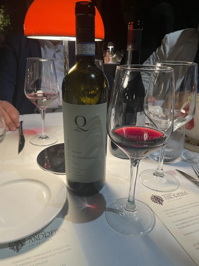 Bottiglia di vino Rosso di Montalcino Querce Bettina servito a tavola con calice e menu del Ristorante Andreina datato 6 giugno 2026.