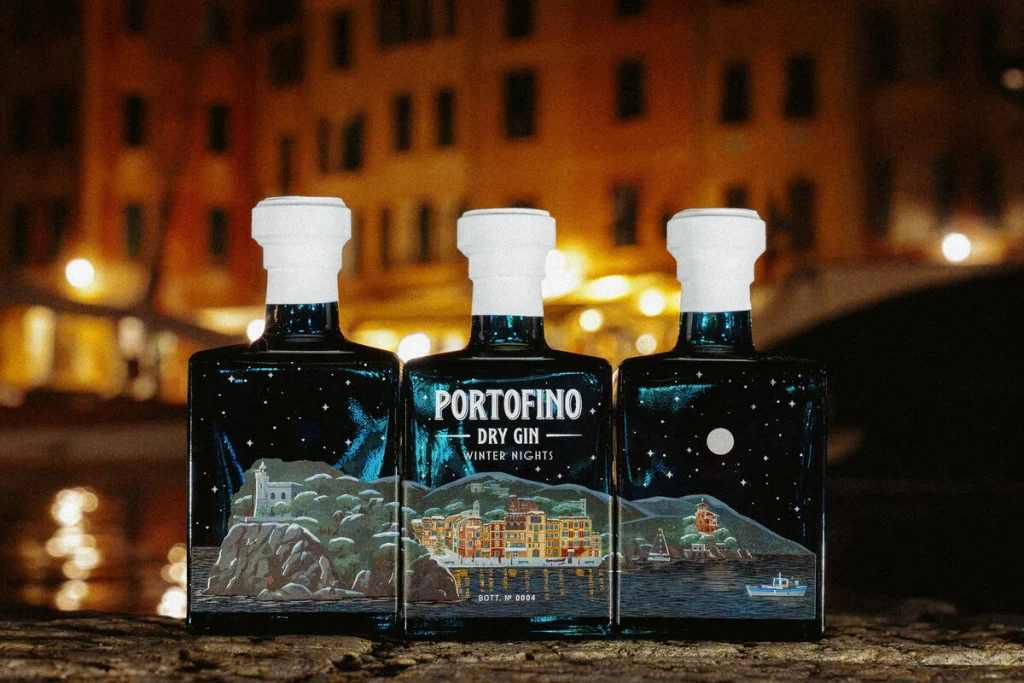 Tre bottiglie affiancate di Portofino Dry Gin Winter Nights che compongono il panorama notturno del borgo ligure e del faro